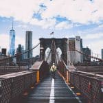 A man walking on a bridge with the skyline of New York on the background